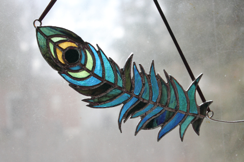 A stained glass peacock feather, made with art glass in various shades of blue and green